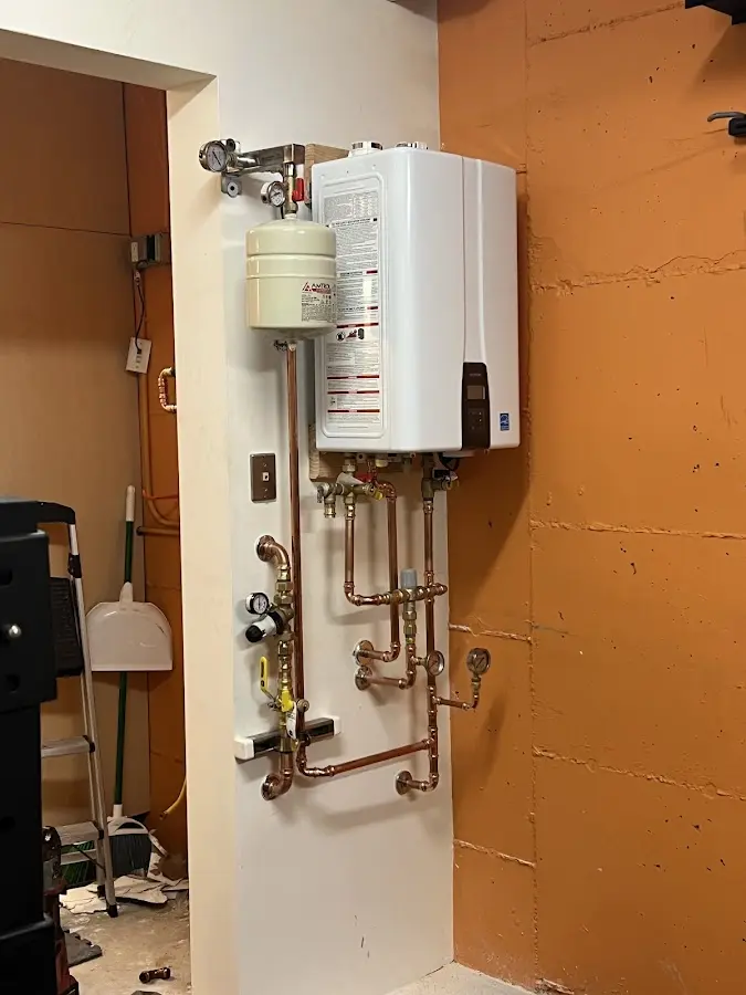 Plumbing technician inspecting water heater connections in Horicon